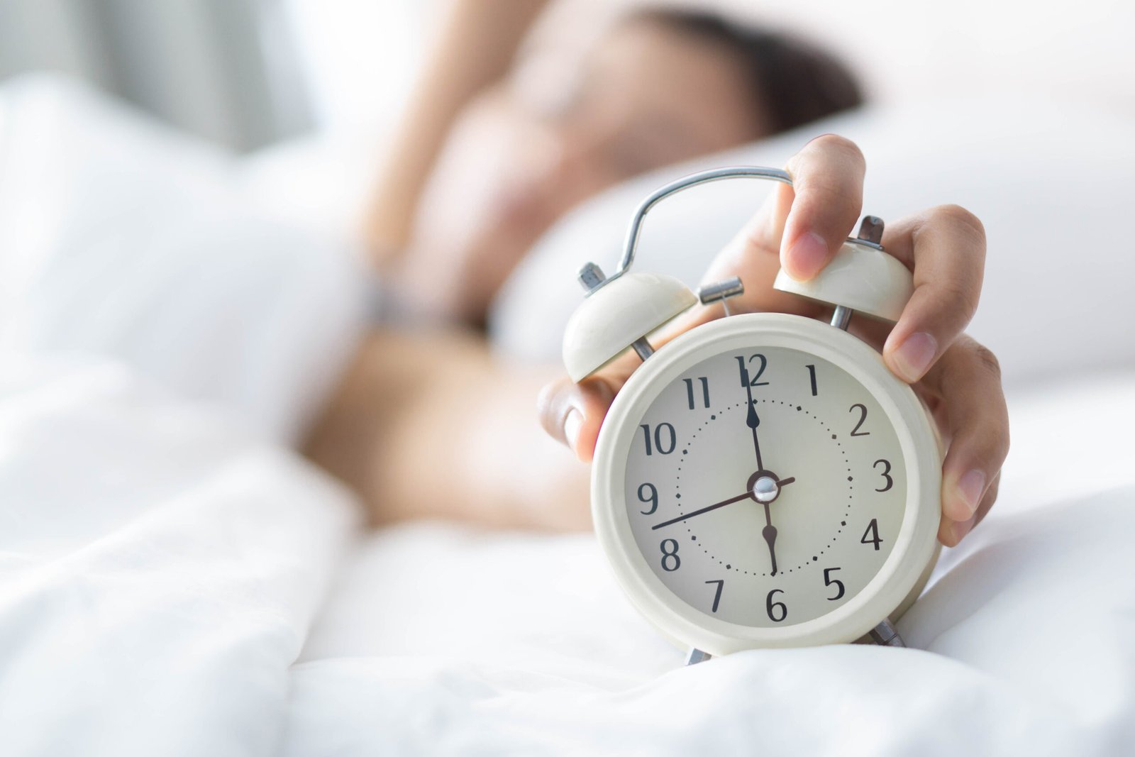 Closeup woman sleeping on bed and hand holding alarm on clock, T