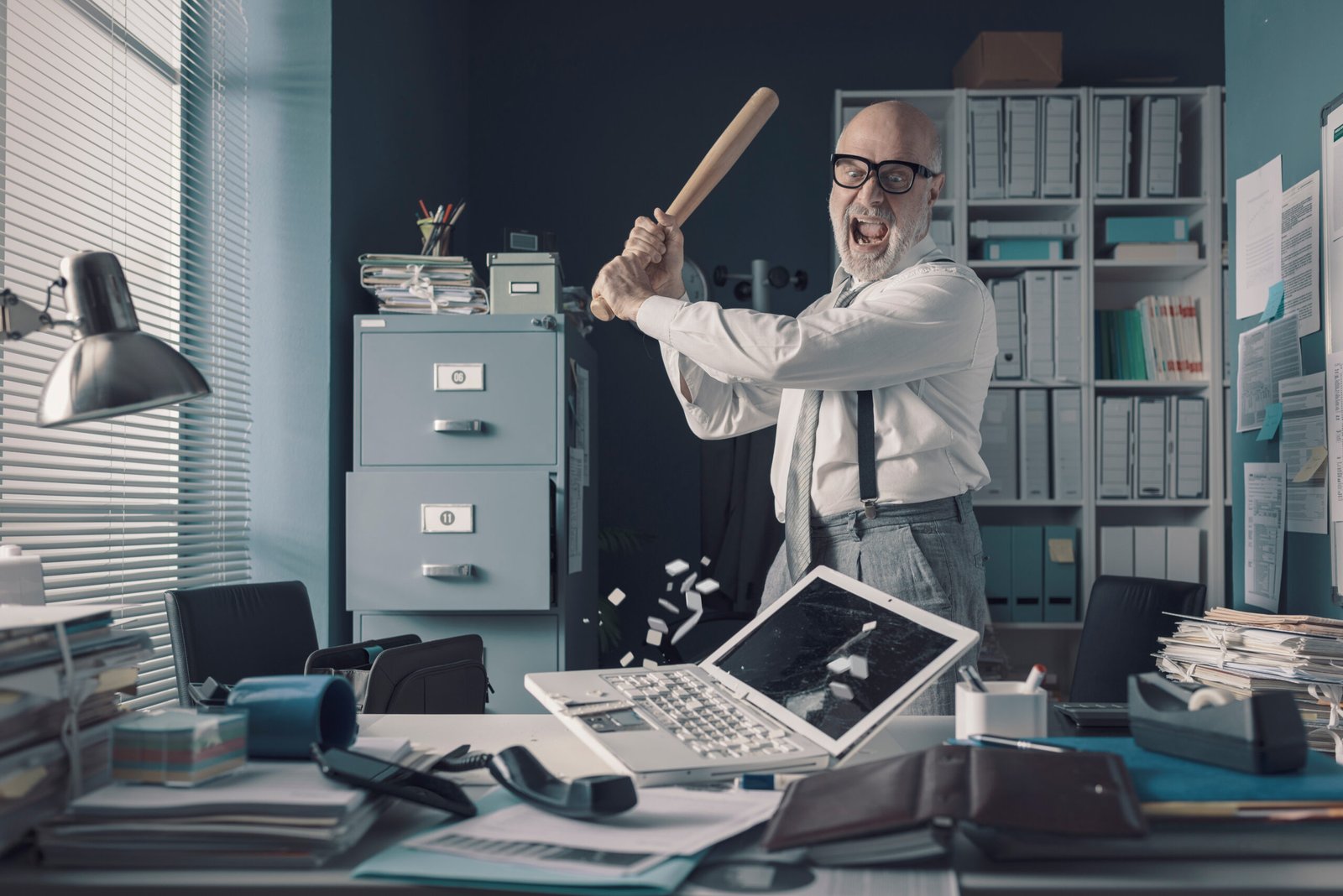 Crazy businessman destryoing his office with a baseball bat