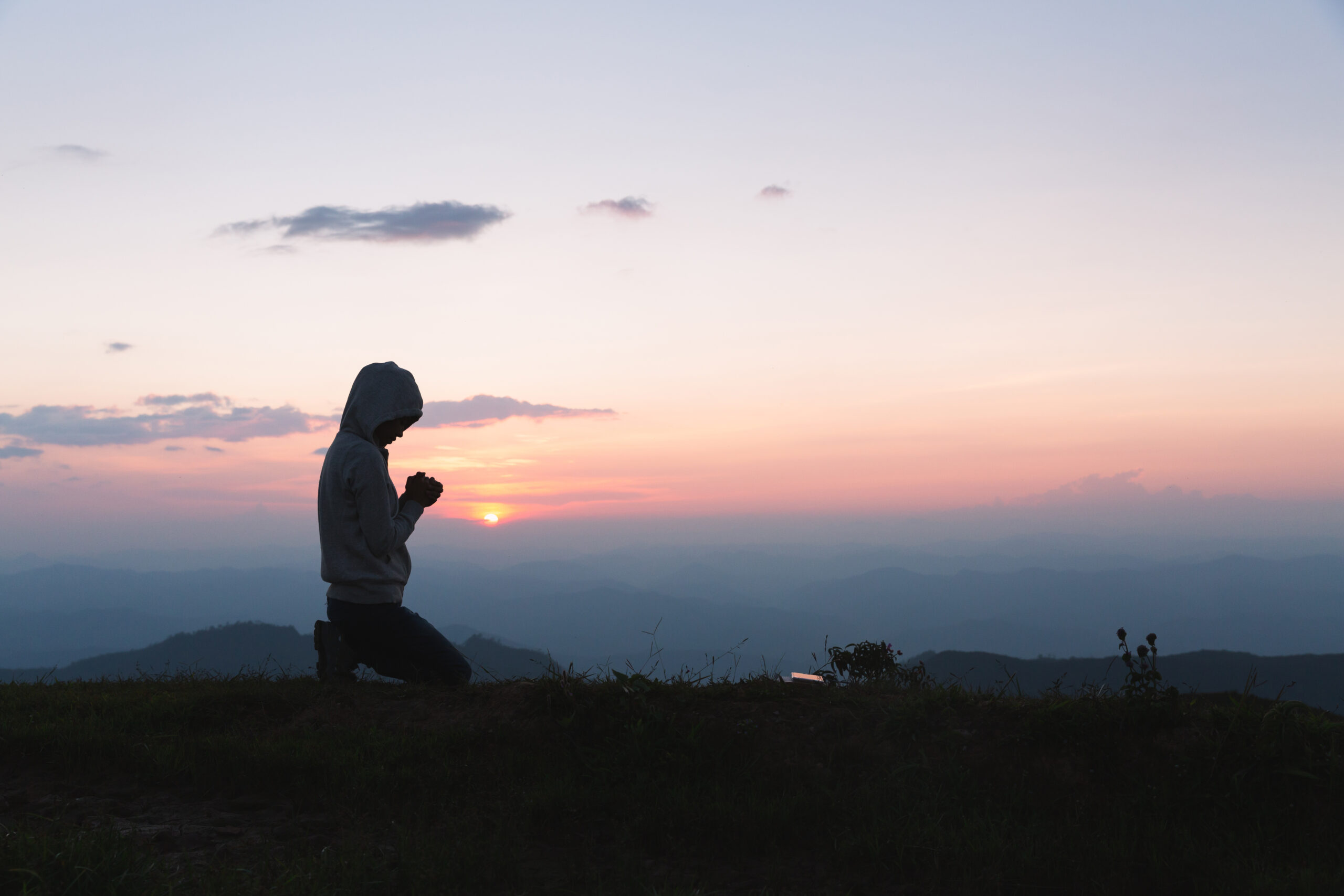 A women is praying to God on the mountain. Praying hands with fa