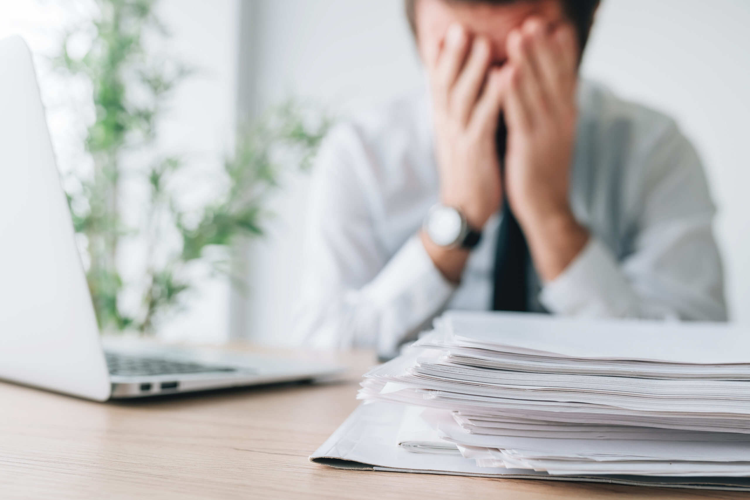 Exhausted businessman overloaded with work in office