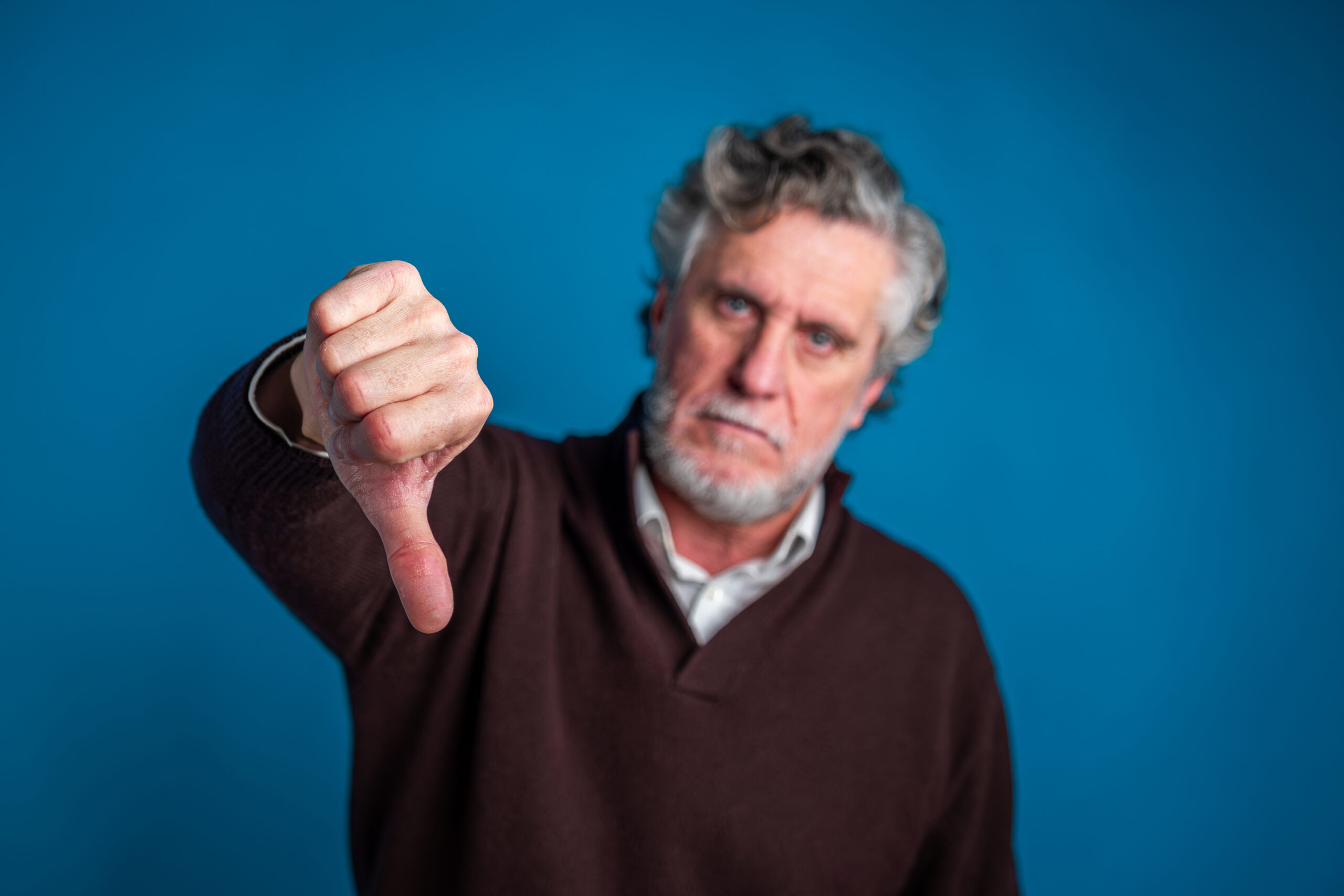 Mature man showing thumbs down for disapproval